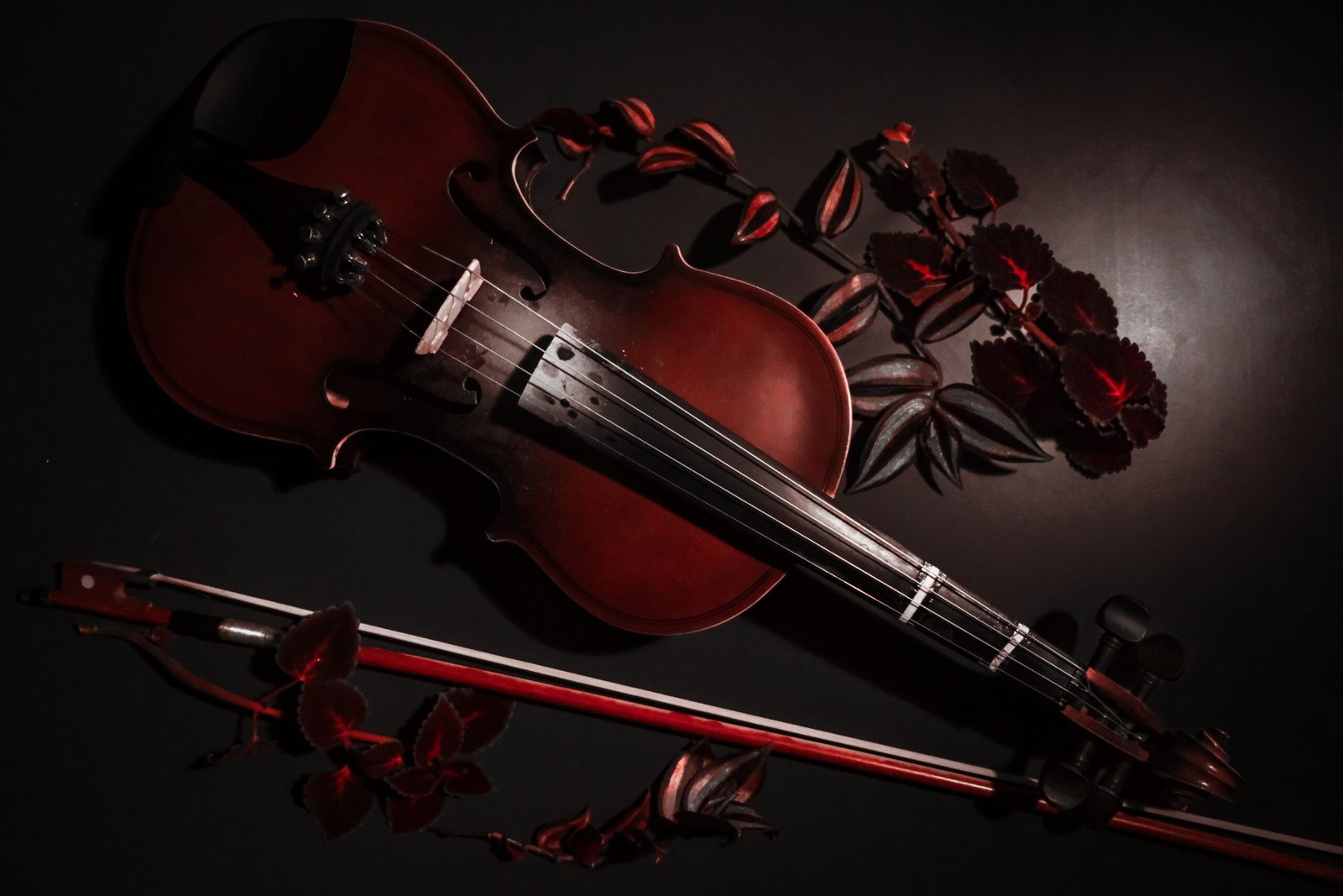 A captivating still life of a violin with dark tones and rich colors, elegantly arranged with red leaves.